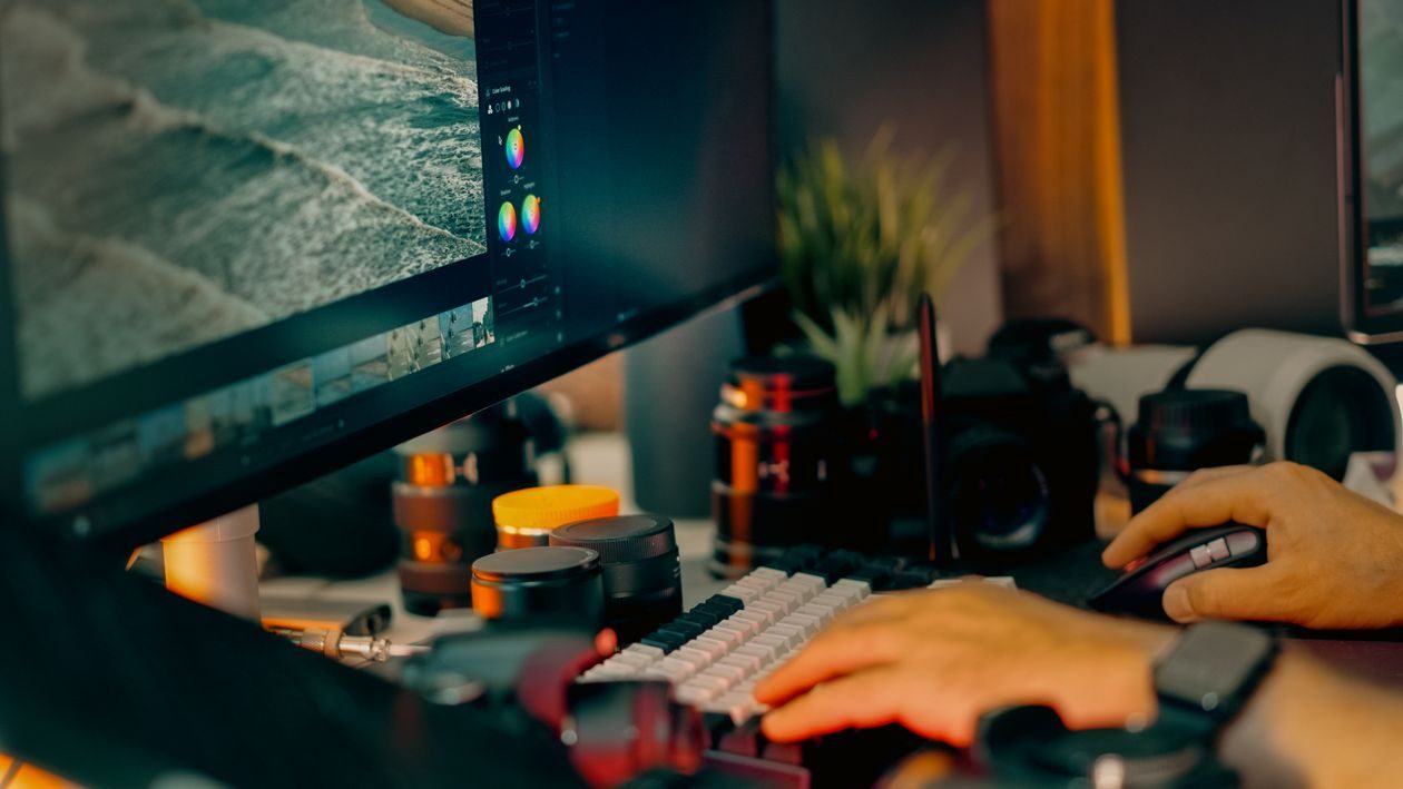 Photo editor working at a desk with image open on screen